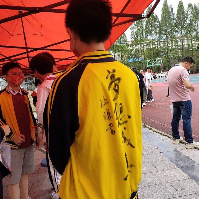 考生抱着校服“求祝福”，书法老师在校服上题字插图中国题字网